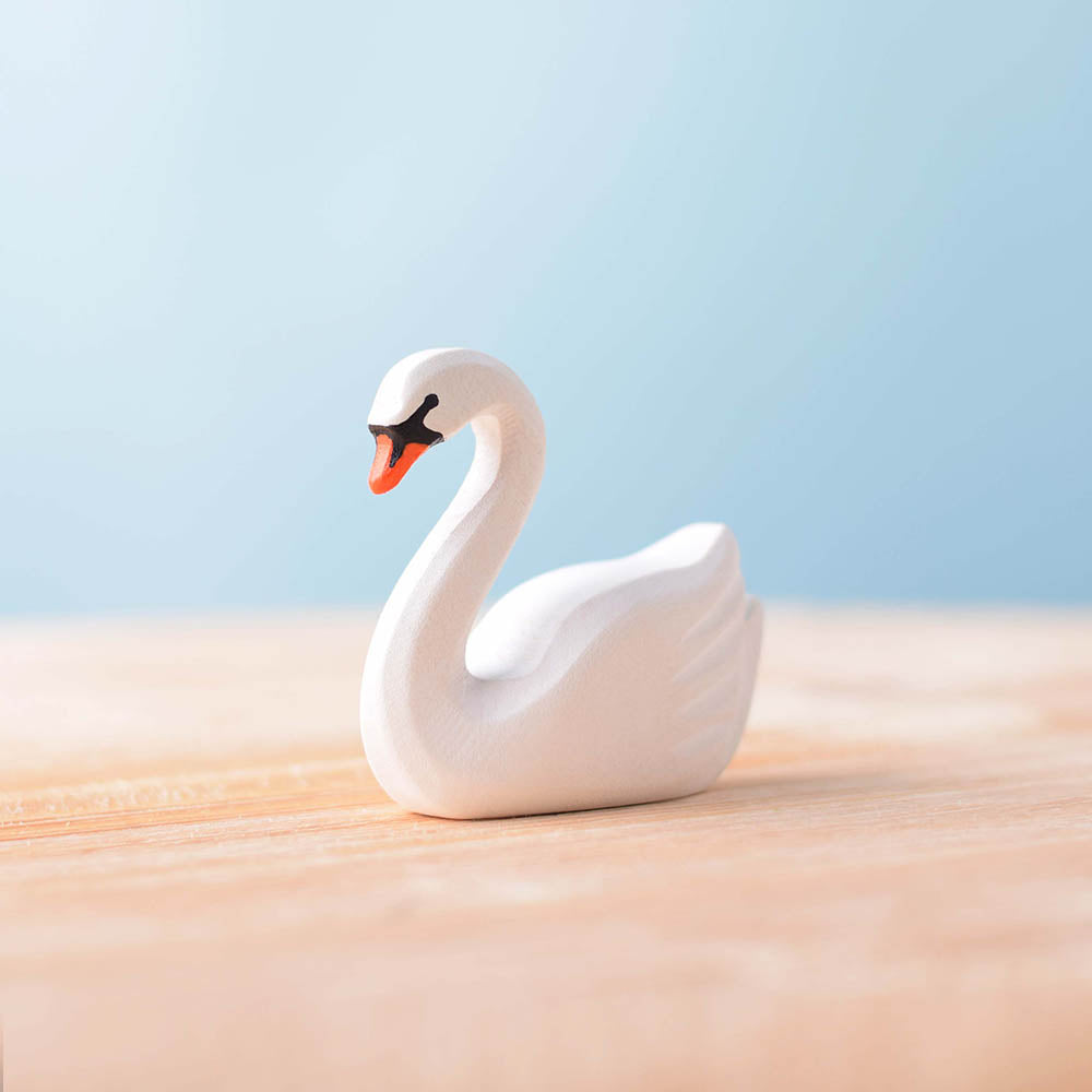 Bumbu childrens handmade wooden swan figure on a wooden worktop in front of a blue background