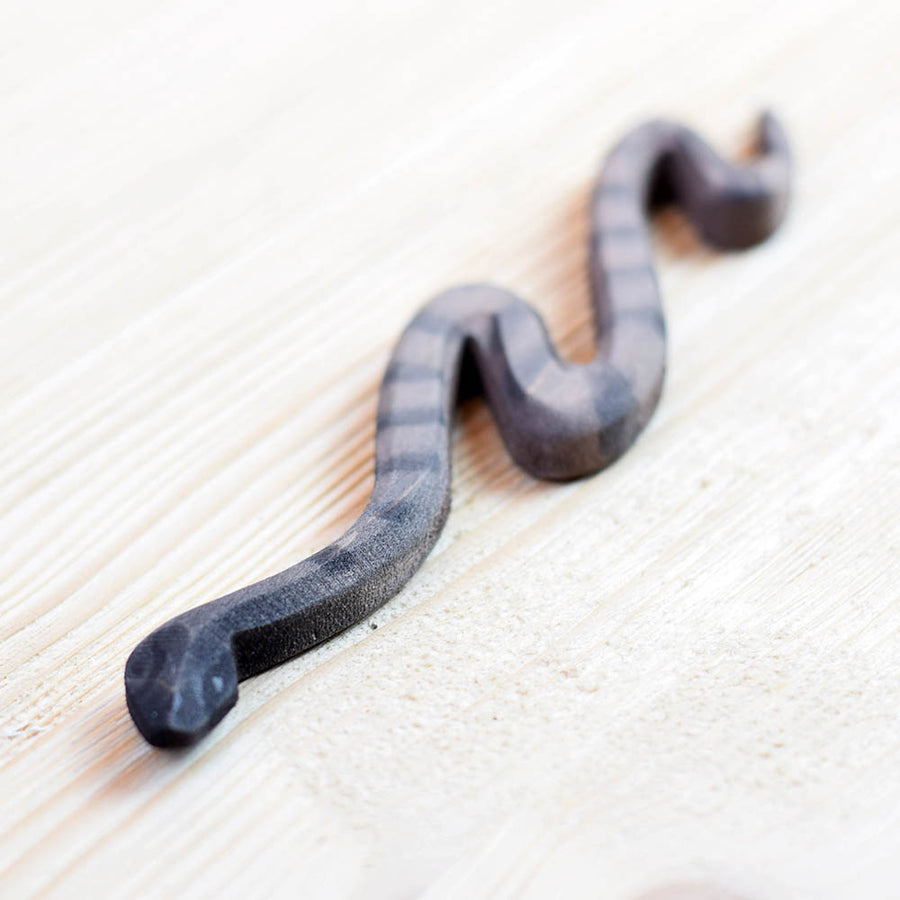 Close up of the Bumbu miniature wooden snake toy on a wooden background