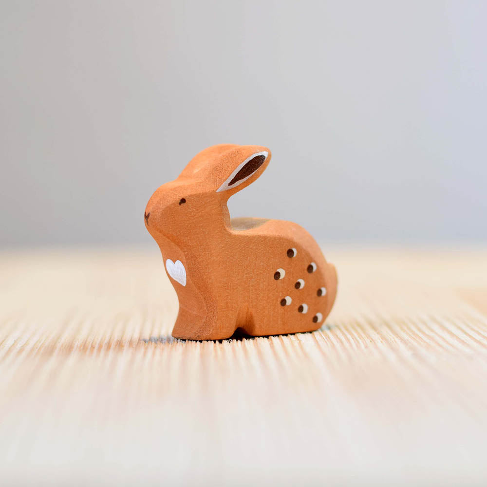 Close up of the Bumbu handmade wooden sitting rabbit toy on a wooden worktop