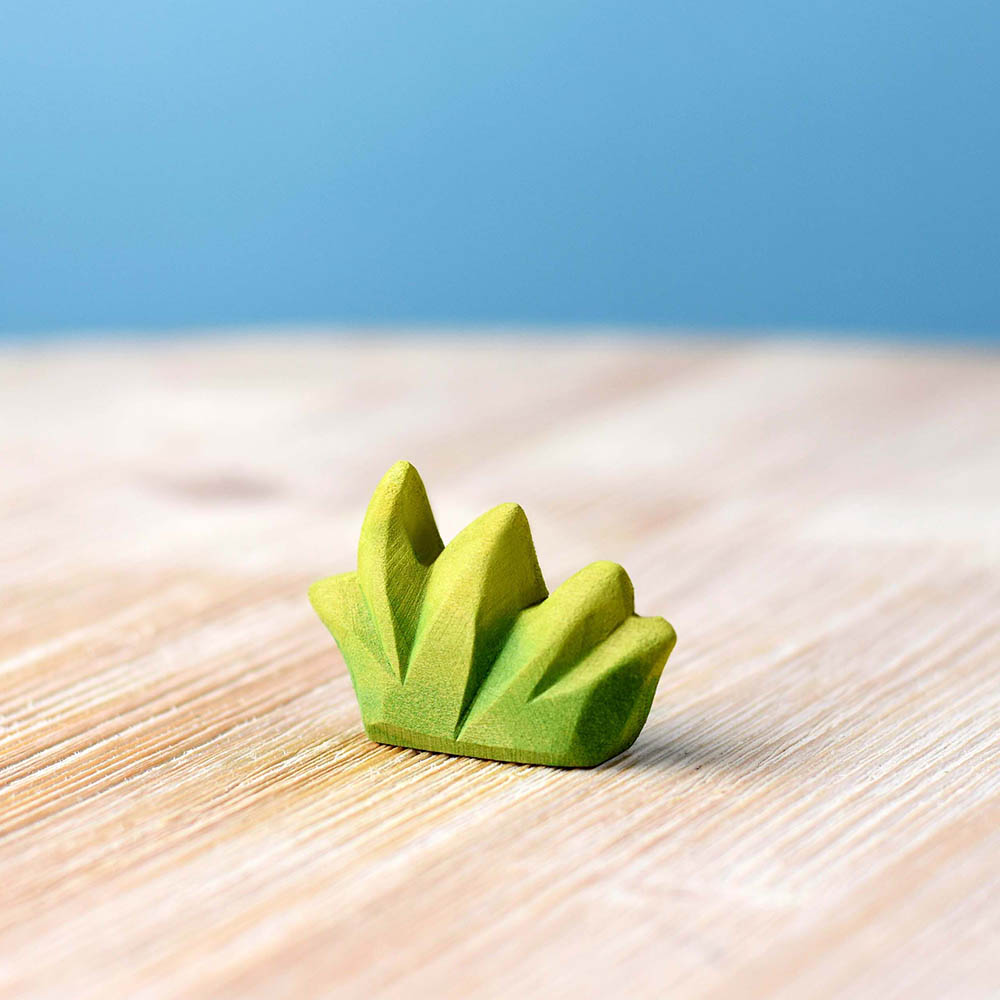 Close up of the Bumbu small wooden grass toy on a wooden worktop