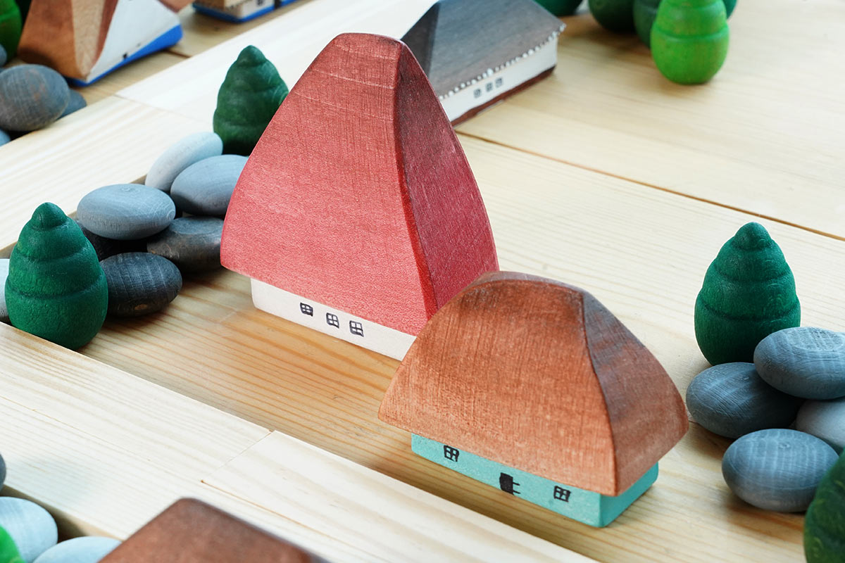 Close up of the Bumbu eco-friendly wooden Crisana houses on a wooden table surrounded by grapat mandala trees