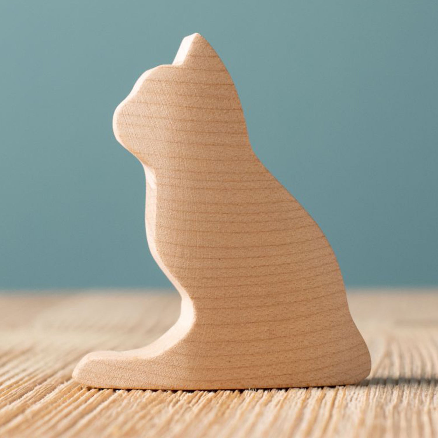 Bumbu Wooden Cat - Paint Your Own. The toy sits on a wooden surface against a blue background.