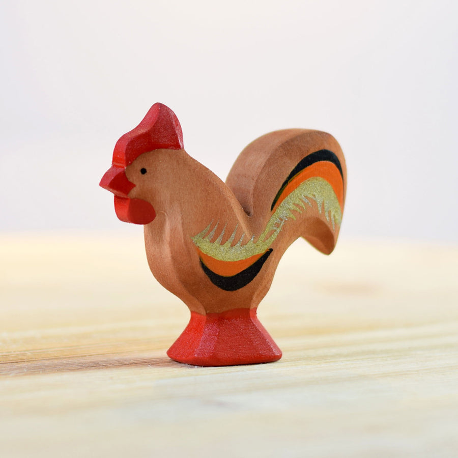 Handmade wooden Bumbu Rooster toy on a wooden table top in front of a white background