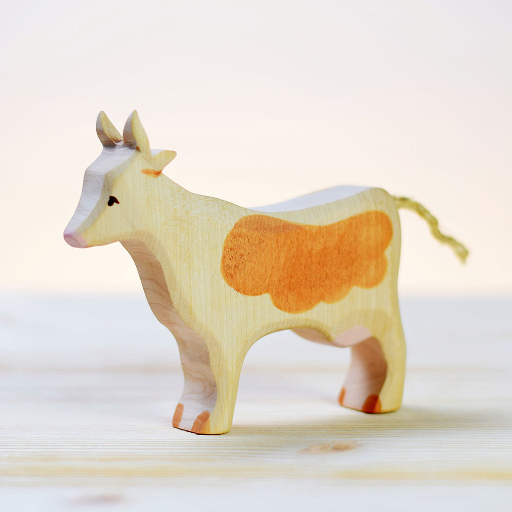 Bumbu sustainable brown and white wooden cow on a light wooden background in front of a white wall