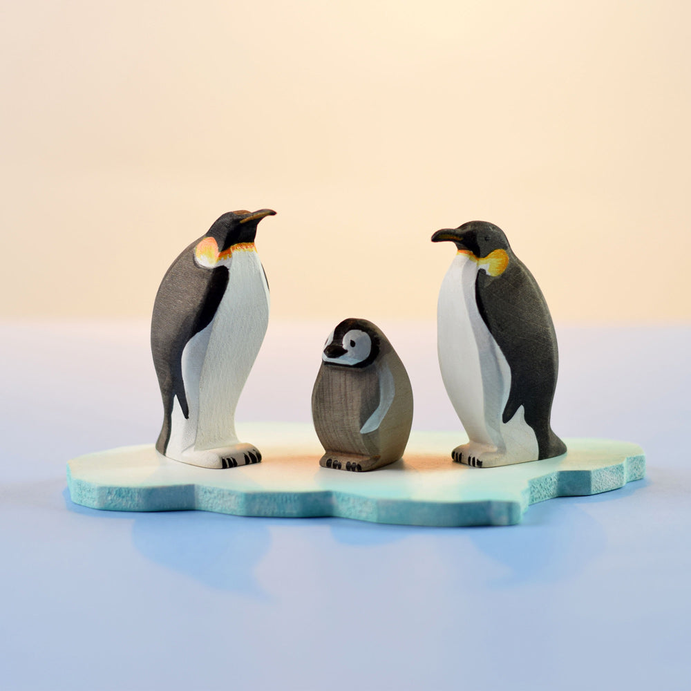 3 Bumbu eco-friendly wooden penguin figures stood on the Bumbu handmade ice floe story block on a blue and white background