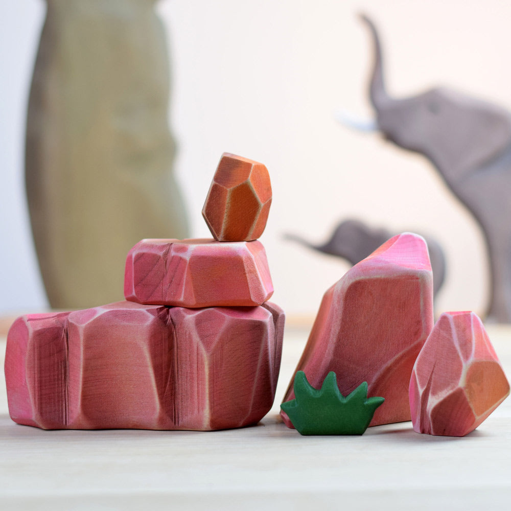 Close up of the Bumbu children's savanna rocks wooden block set laid out on a white work top in front of some bumbu toy elephants