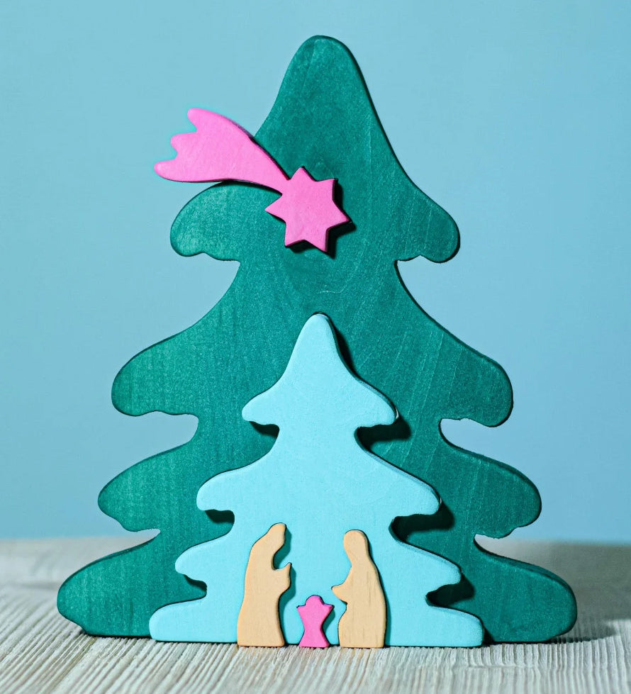 A Bumbu Christmas Tree Nativity Puzzle in a Fuchsia colour way placed on a wooden surface. 