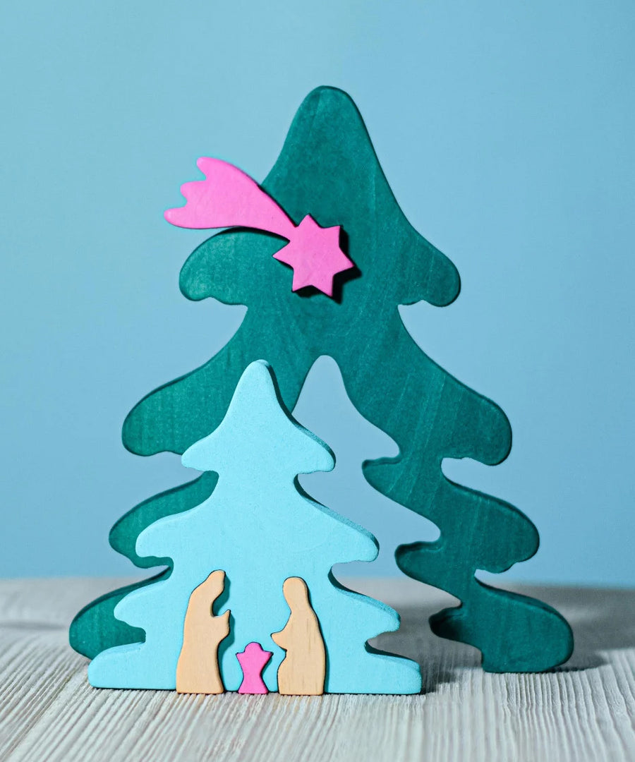 A Bumbu Christmas Tree Nativity Puzzle in a Fuchsia colour way placed on a wooden surface. The blue tree piece has been pulled to the front.