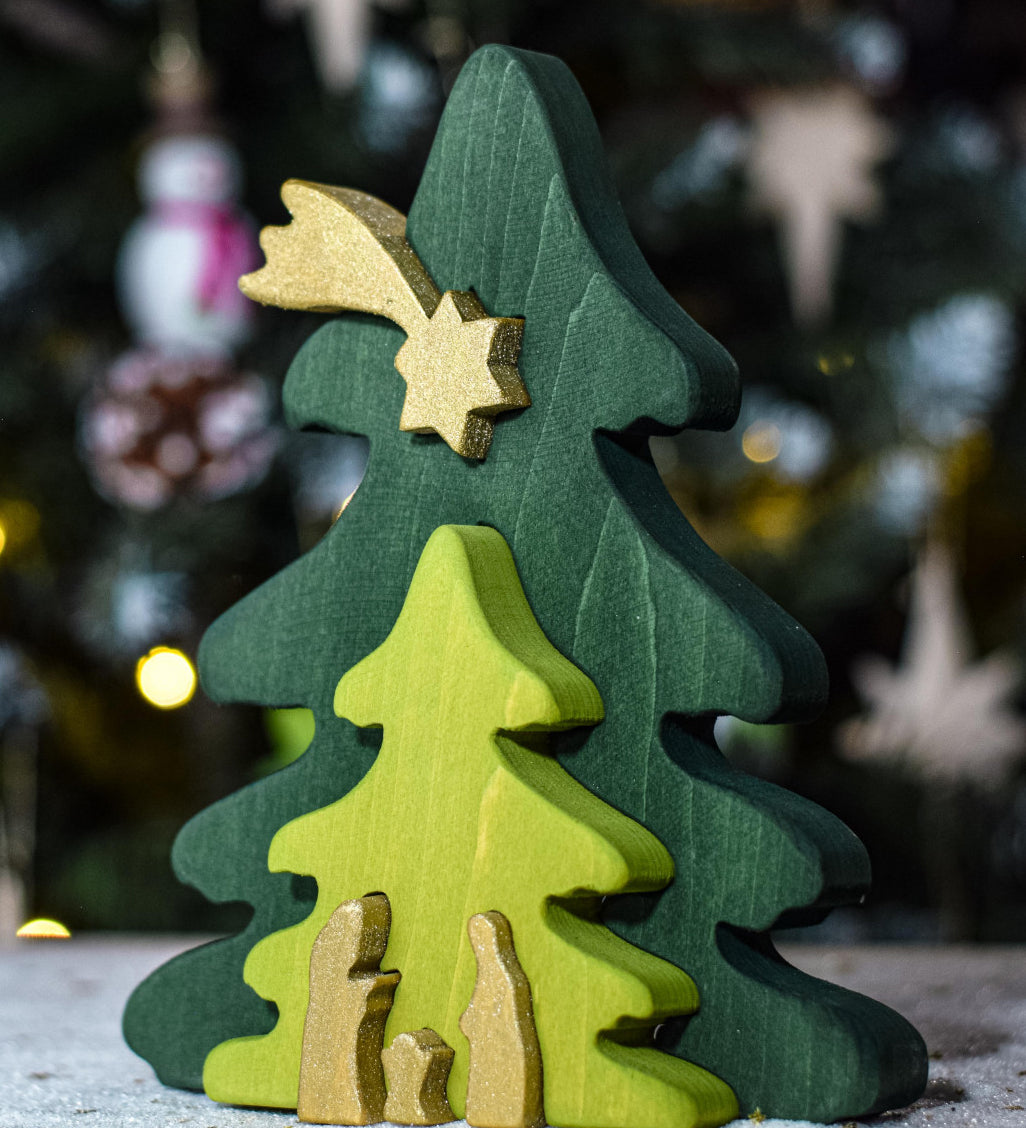 A Bumbu Christmas Tree Nativity Puzzle in the Gold colour way placed in front of a Christmas tree. 