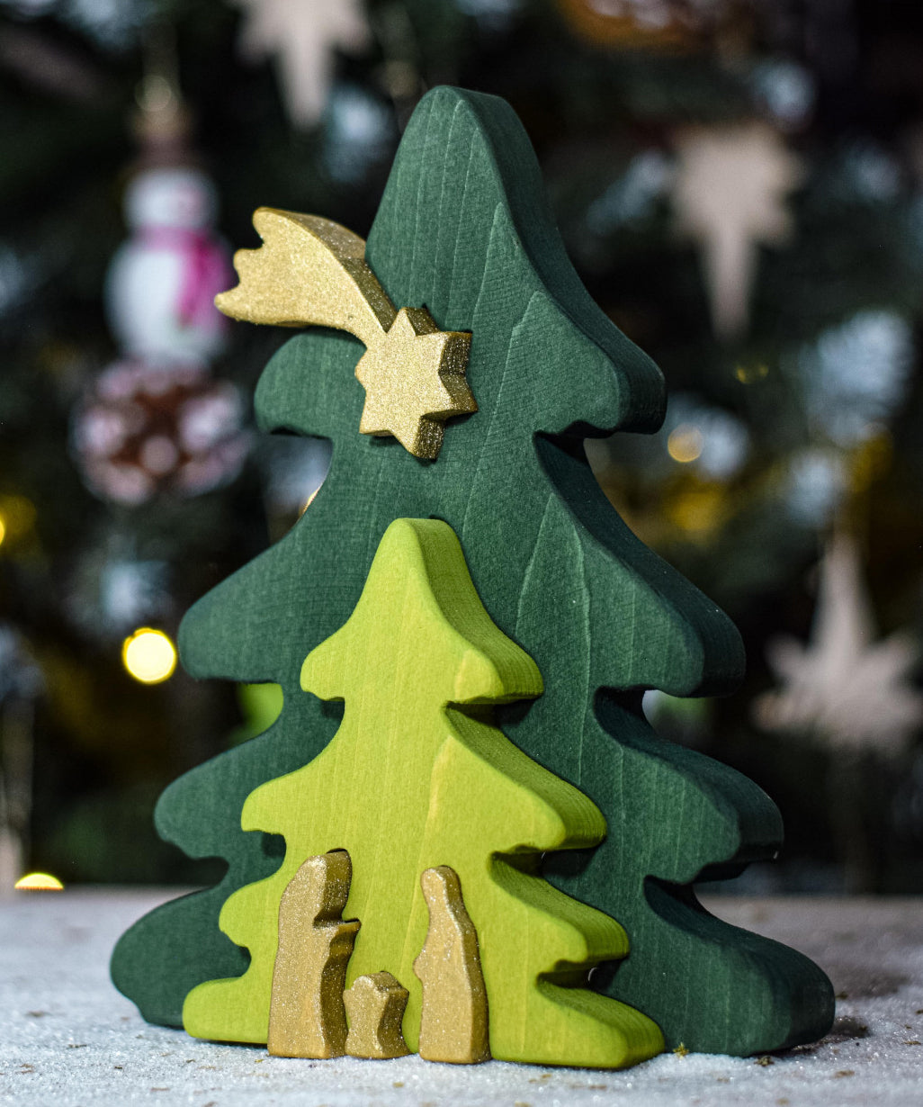 A Bumbu Christmas Tree Nativity Puzzle in the Gold colour way placed in front of a Christmas tree. 