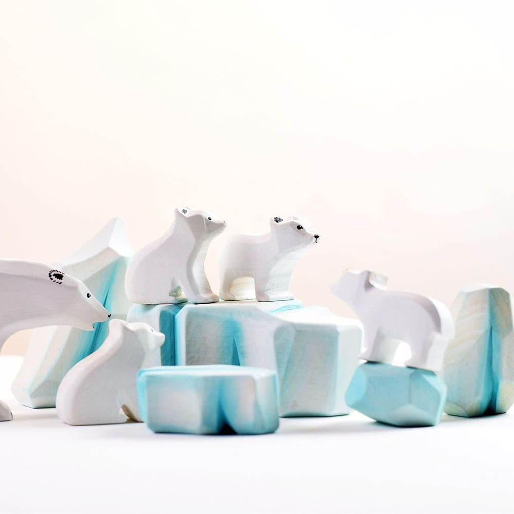 Bumbu handmade wooden icy rock toys lined up on a wooden worktop in front of a blue background