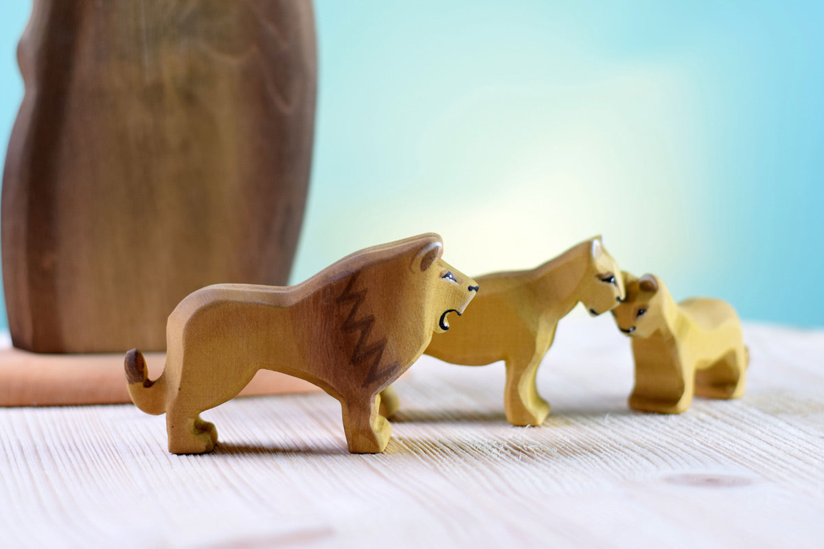 female and baby lion toys stood on a white wooden background