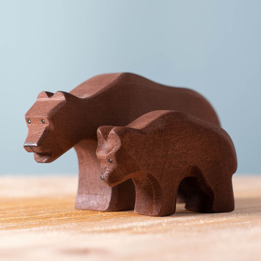 Bumbu plastic-free wooden bear and bear cub animal toys on a wooden worktop in front of a blue background