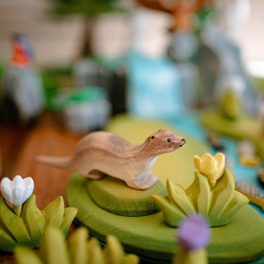 Close up of the Bumbu brown otter figure on a green wooden garden scene