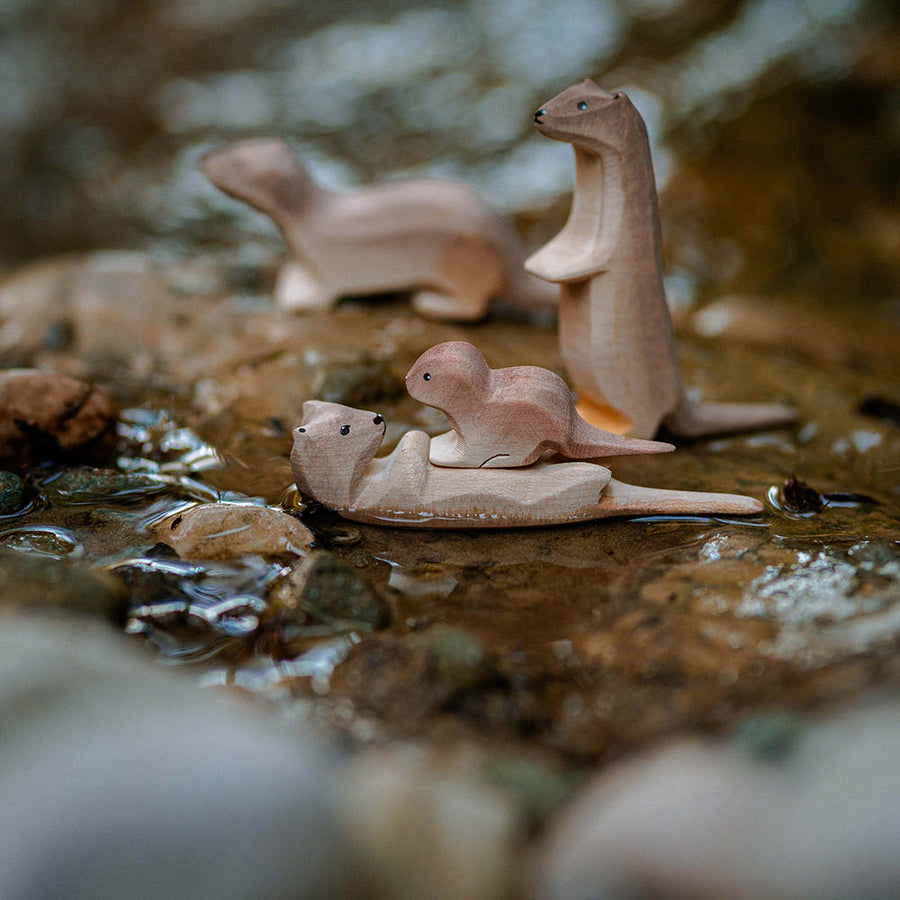 Close up of the Bumbu wooden otter and baby otter toy figures in a small rocky stream