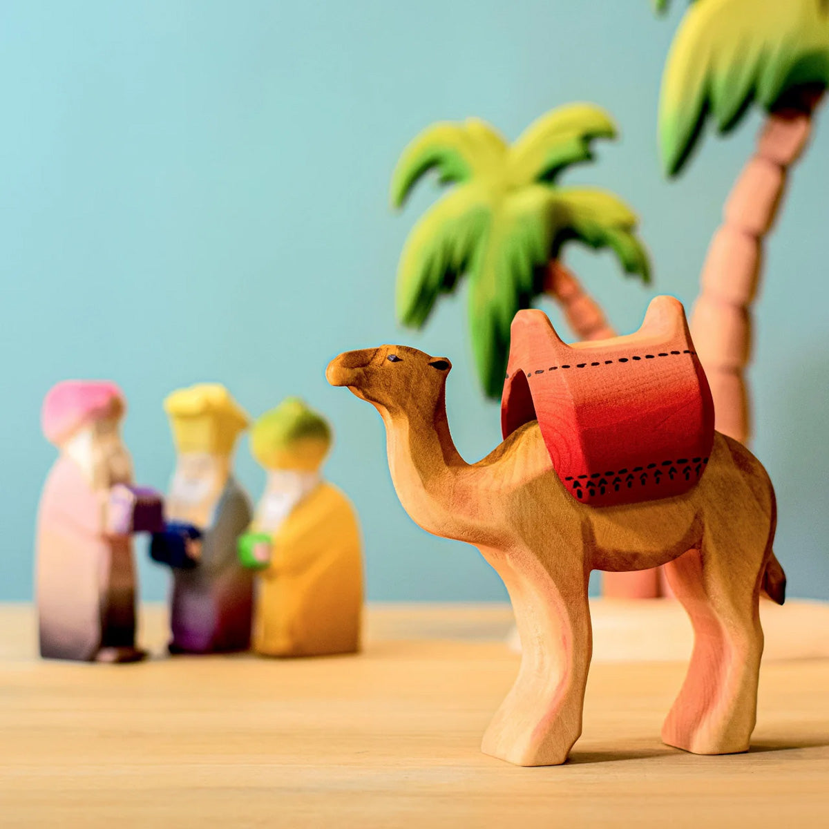 Bumbu handmade wooden camel figure on a blue background and wooden table