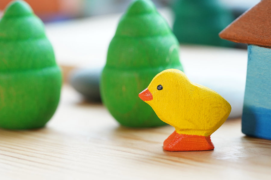 Bumbu small wooden chick figure on a wooden table in front of a Grapat mandala tree