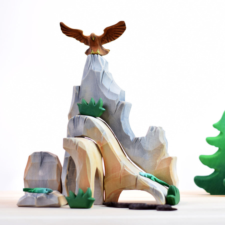 Bumbu wooden eagle toy figure on top of a large wooden rock toy set in front of a white background