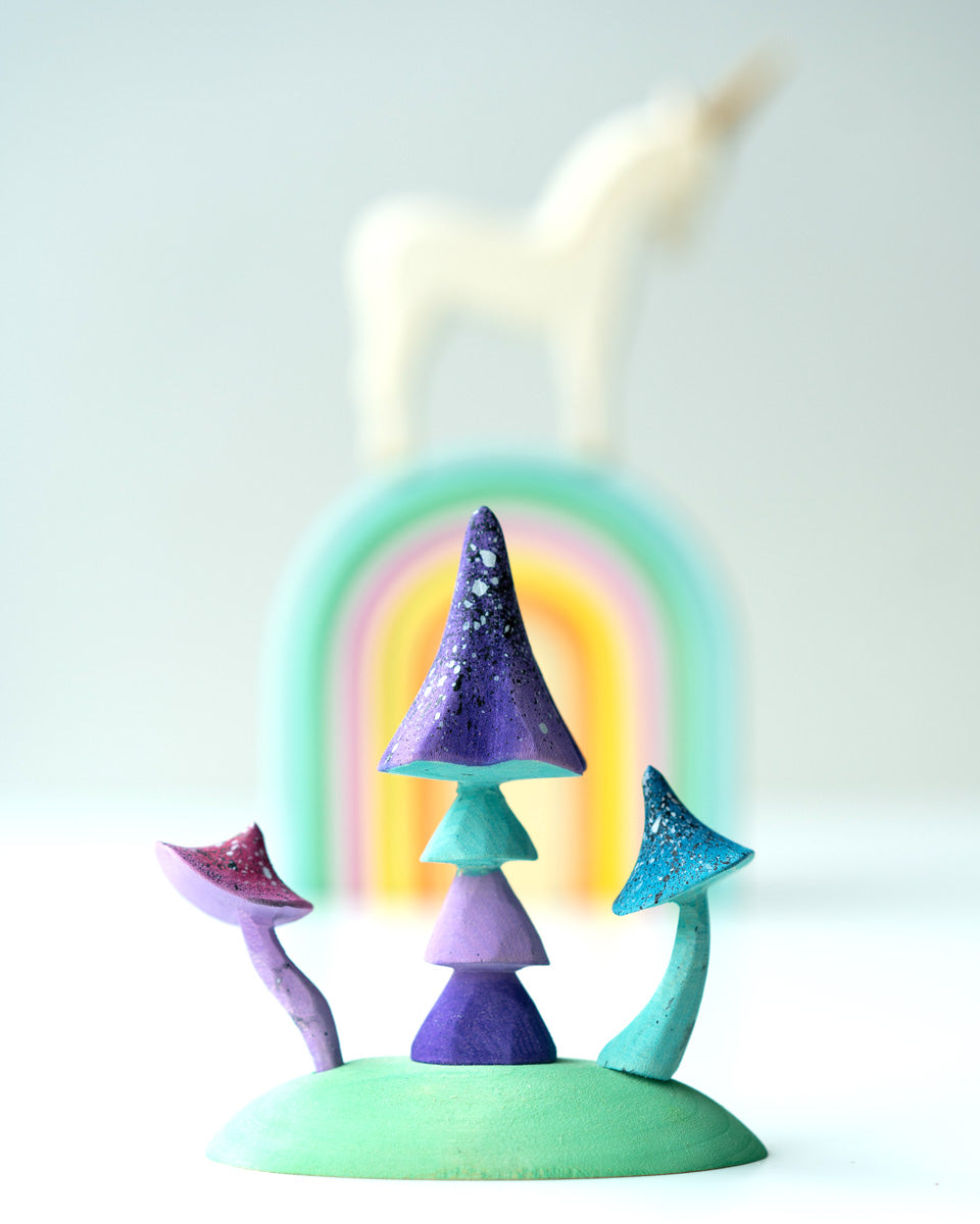 Close up of the Bumbu plastic-free enchanted mushroom toys on a white background in front of a stacking rainbow and unicorn figure