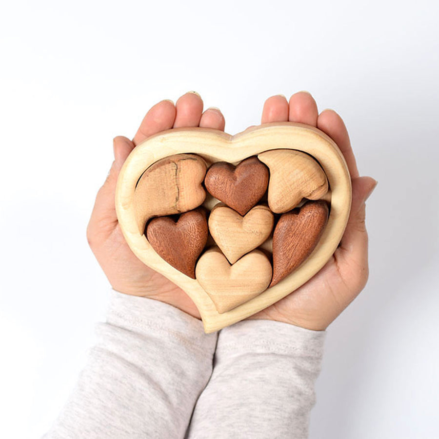 Close up of hands holding the Bumbu plastic free wooden puzzle set on a white background