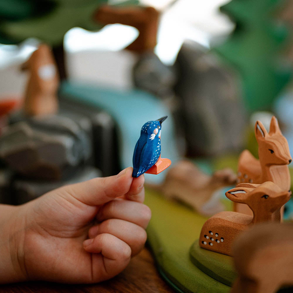 Close up of a childs hand holding the Bumbu plastic-free wooden kingfisher bird toy