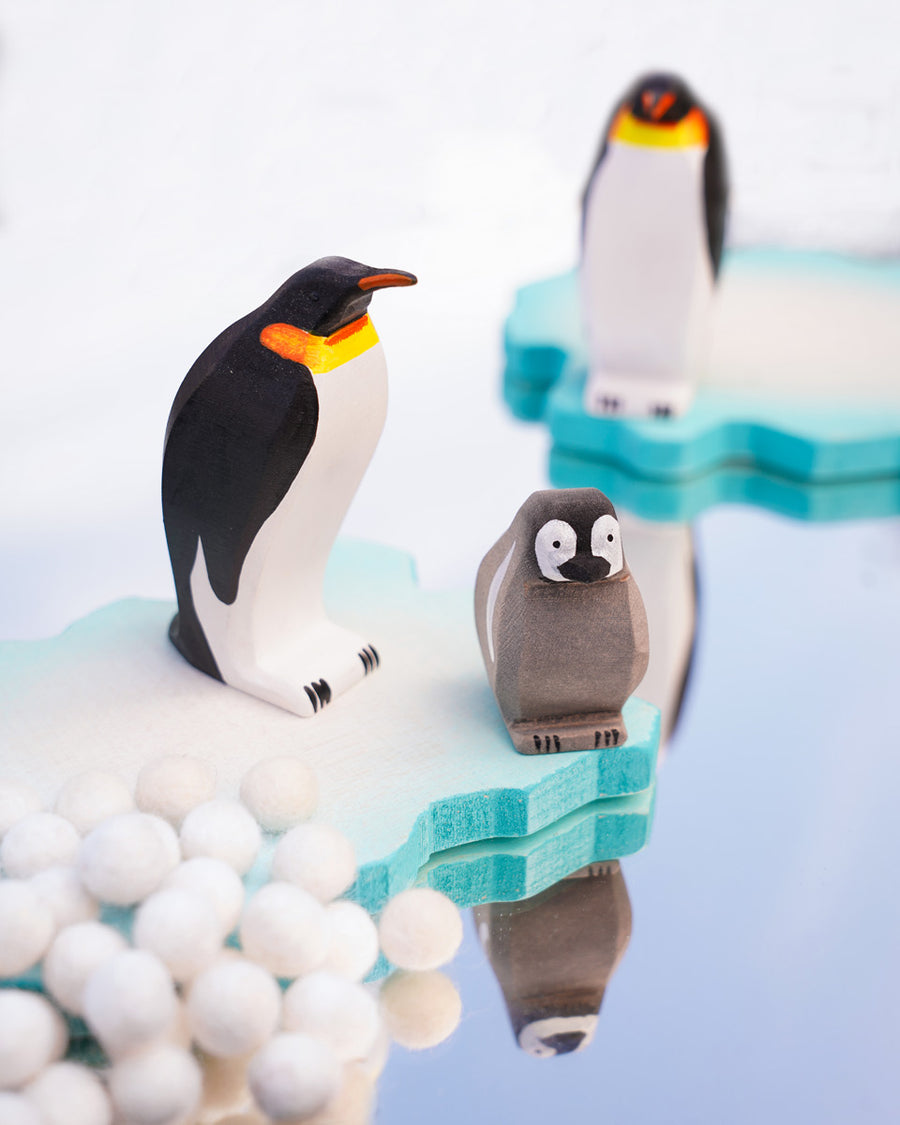 female and baby penguin wooden toy figures stood on a white background