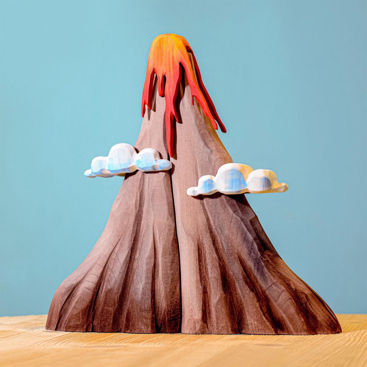 Bumbu Wooden Volcano Set. The toy sits on a wooden surface against a blue background.