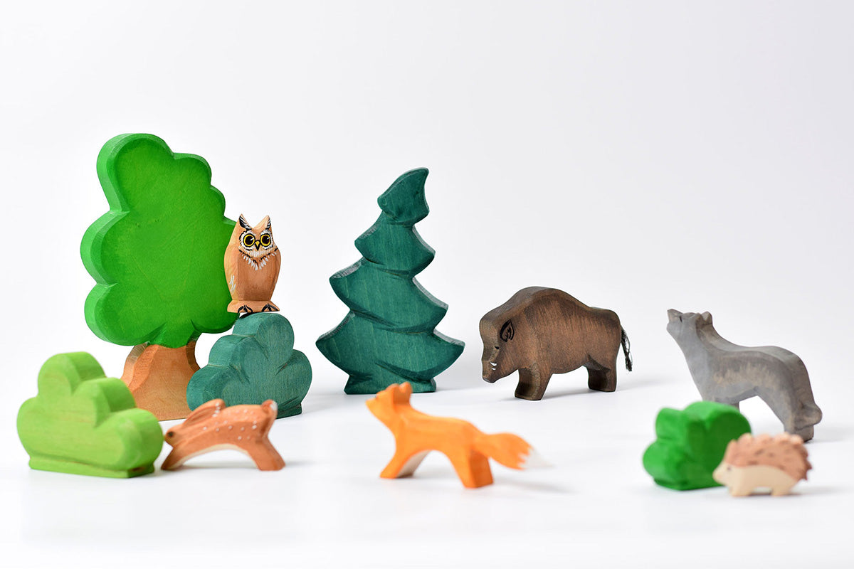 Bumbu large tree and other handmade wooden Bumbu toys scattered on a white background to make an animal nature scene