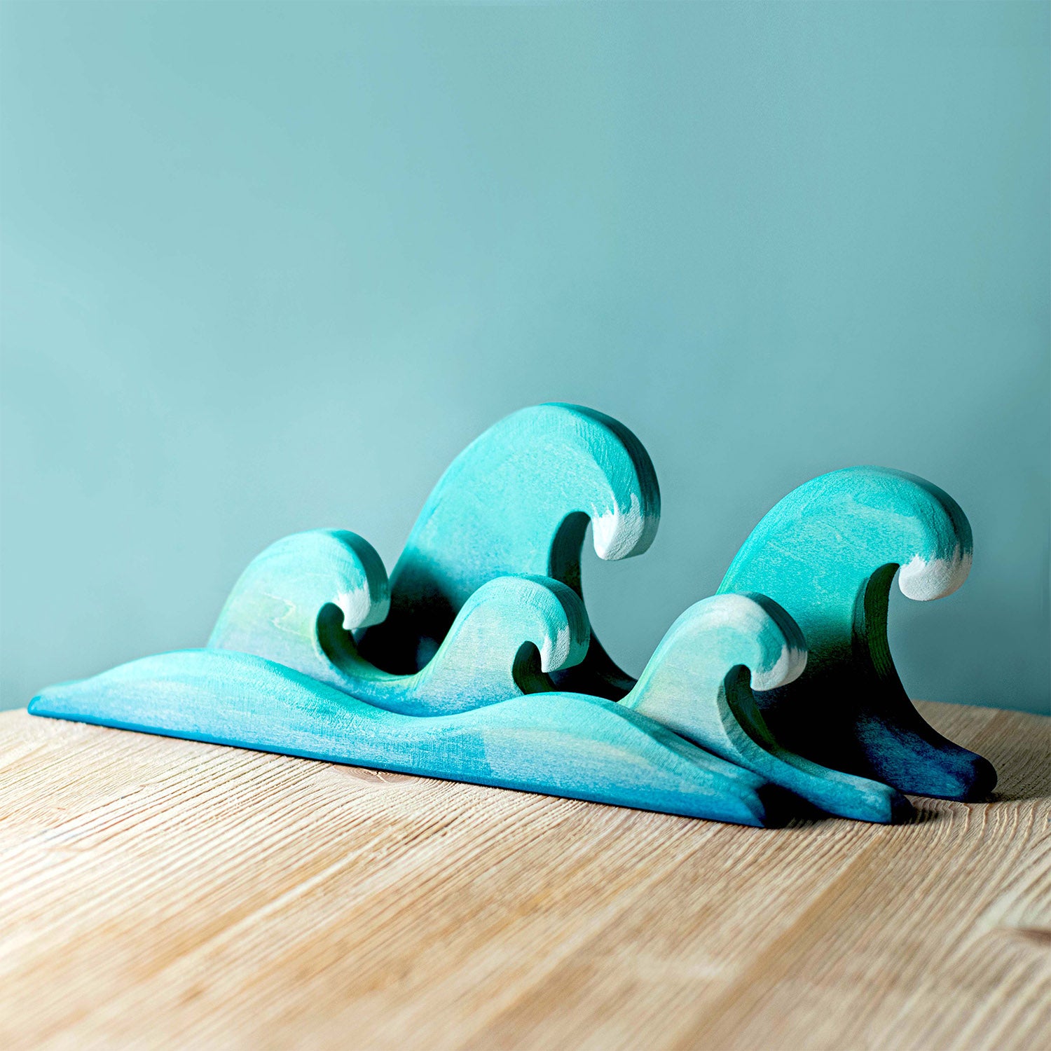 Bumbu Wooden Waves. The toy sits on a wooden surface against a blue background.