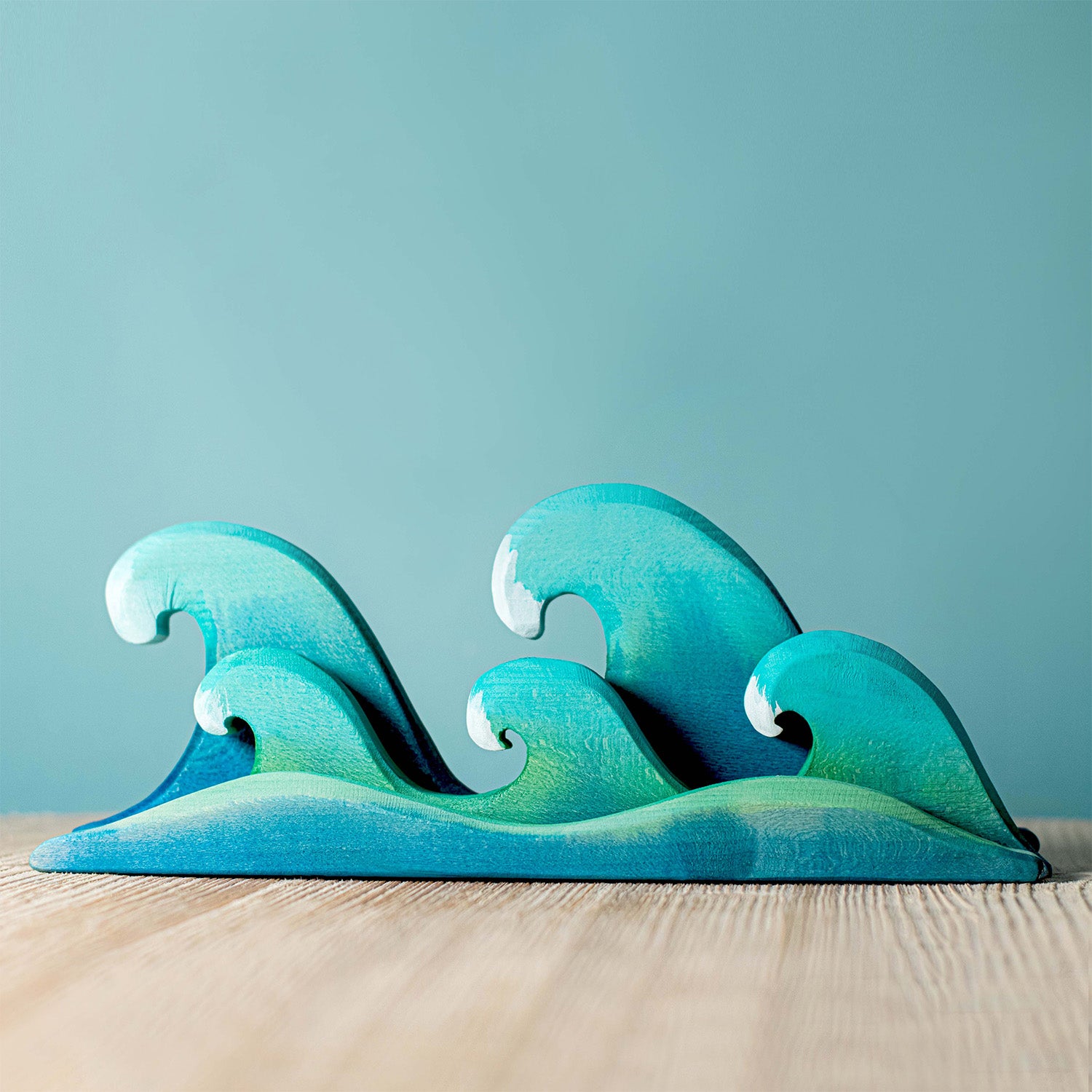 Bumbu Wooden Waves. The toy sits on a wooden surface against a blue background.