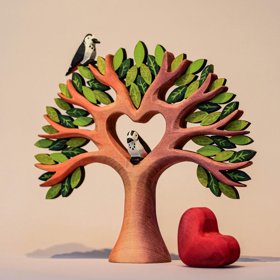 with a removable wooden red heart in the centre. The tree is displayed on a wooden table with a blue background