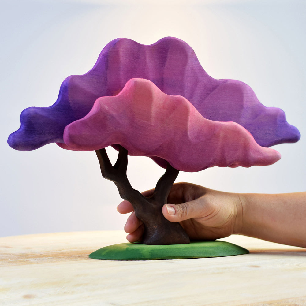 Hand holding the plastic free eco-friendly wooden Bumbu japanese maple tree toy on a white wooden background