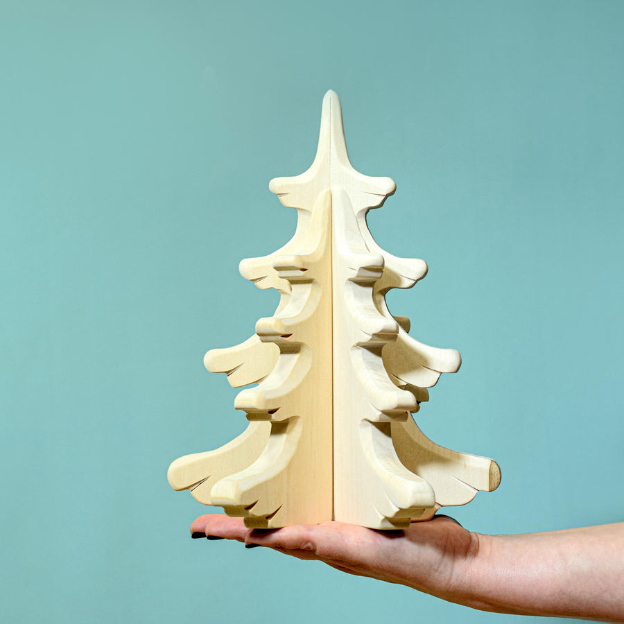 Person holding the Bumbu Large Natural Sugar Pine Tree in their hand pictured on a blue background