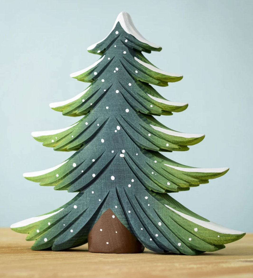 A large Bumbu Snowy Fir Tree placed on a wooden surface. 