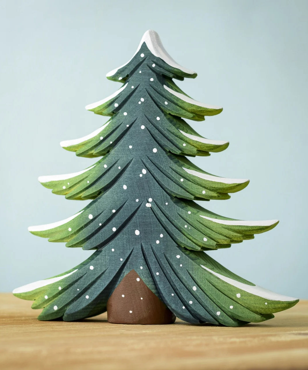 A large Bumbu Snowy Fir Tree placed on a wooden surface. 