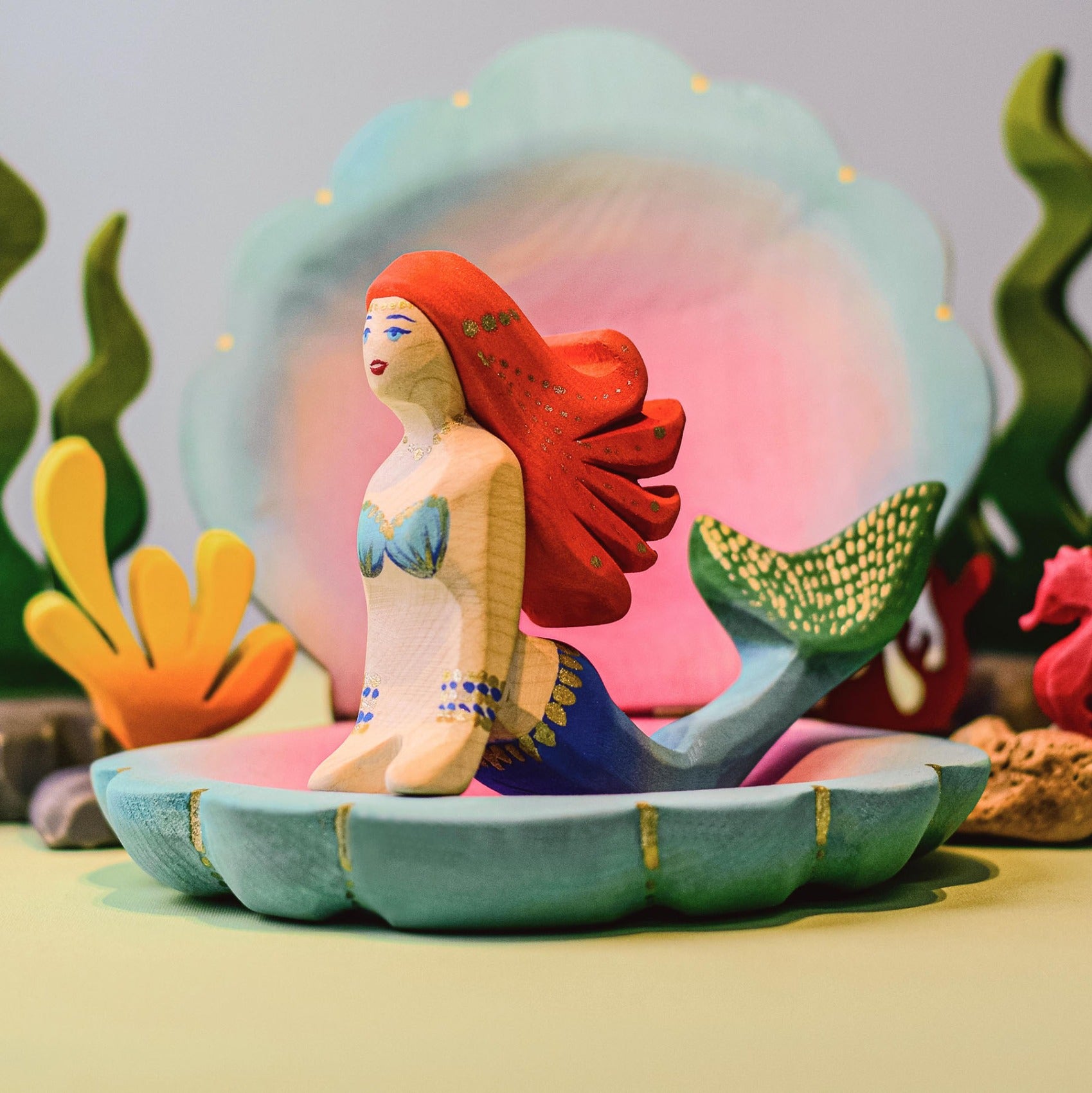 with two Bumbu mermaids posed on top in an aquatic scene.