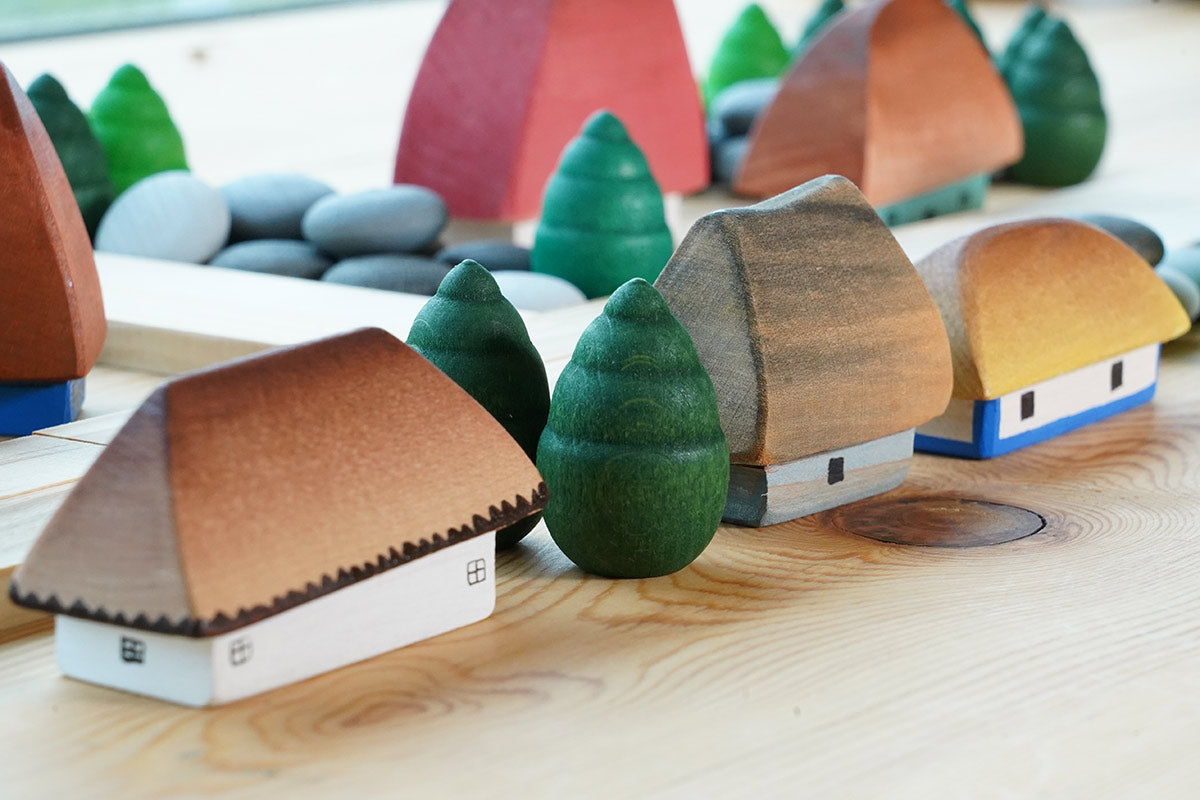 Bumbu Moldova handmade wooden miniature houses lined up on a wooden table next to some grapat mandala trees