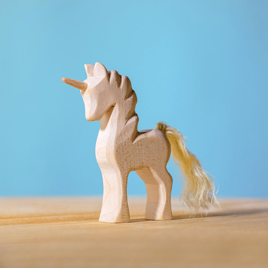 Bumbu Natural Wood Unicorn placed on a wooden surface with a blue wall in the background