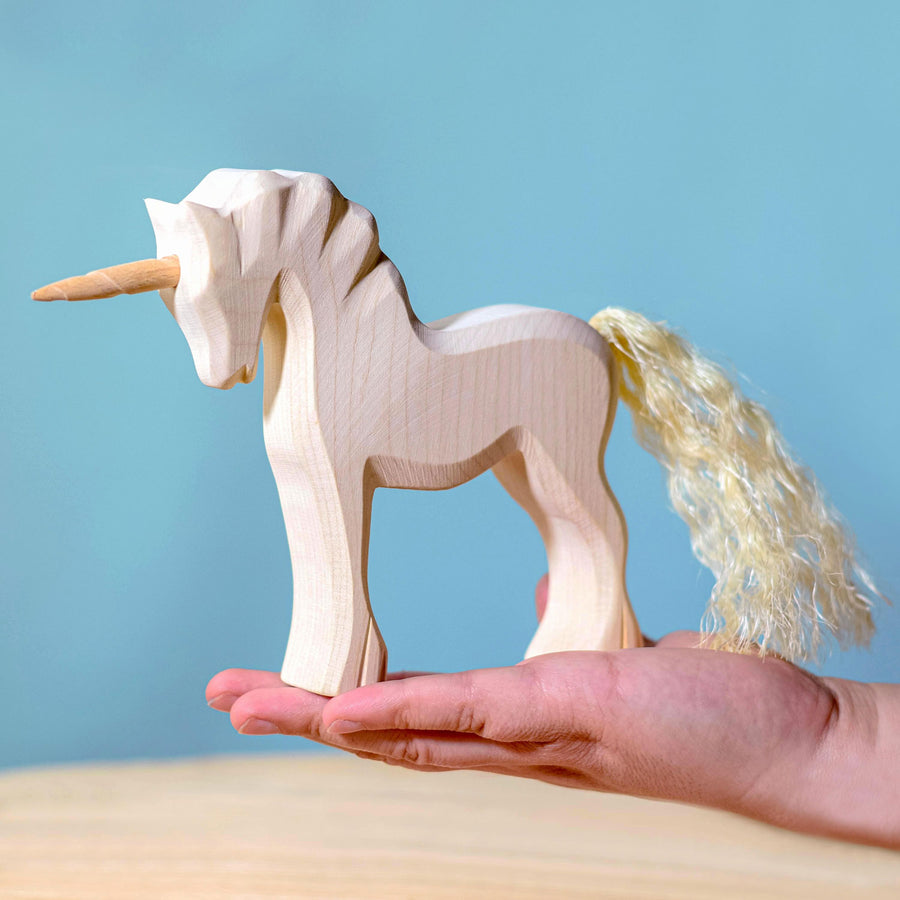 Bumbu Natural Wood Unicorn pictured in an adults hand