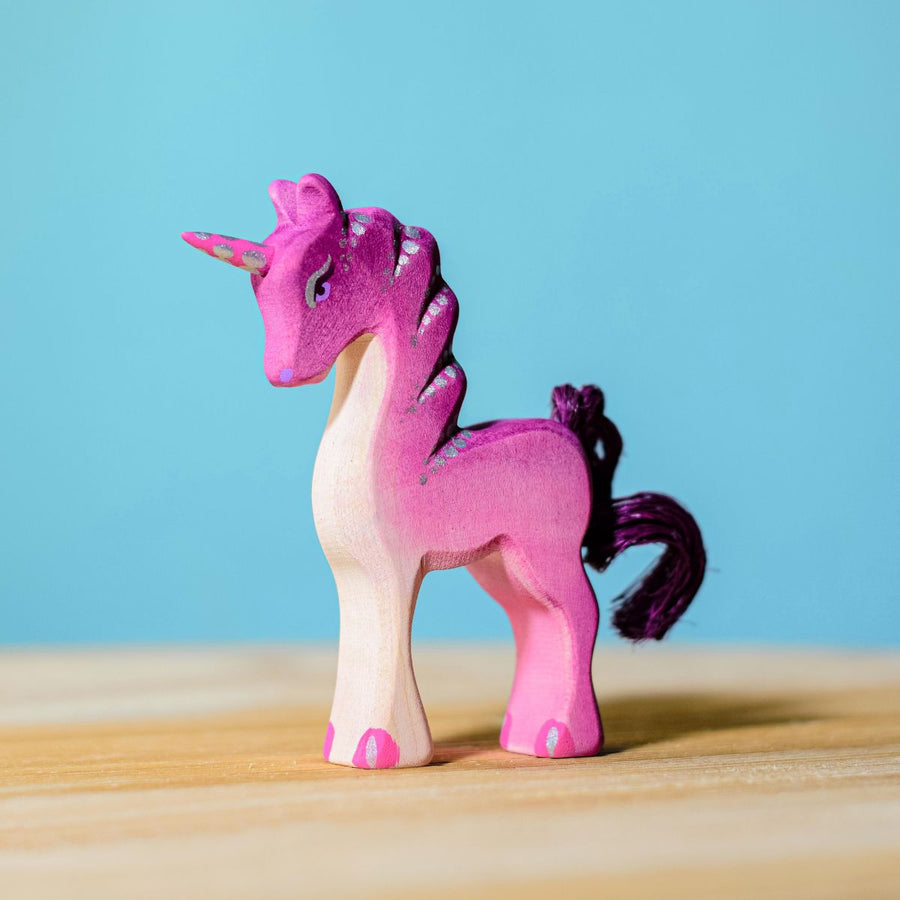 Bumbu Pink Baby Unicorn placed on a wooden surface with a blue wall behind