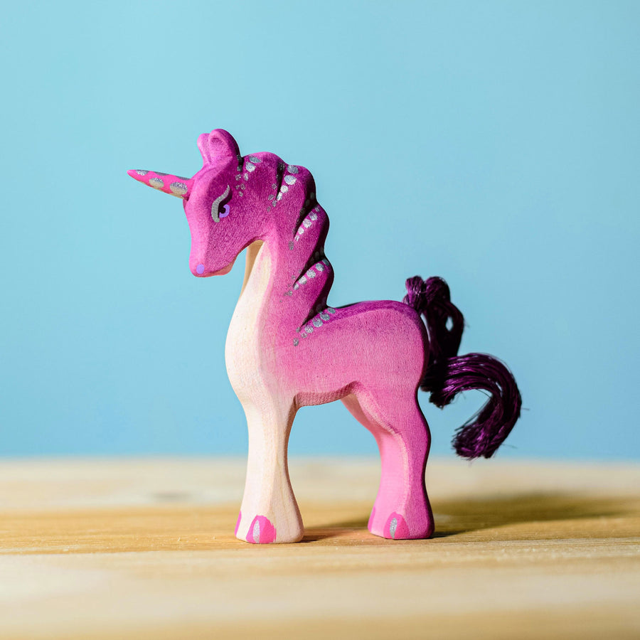 Bumbu Pink Baby Unicorn placed on a wooden surface with a blue wall behind