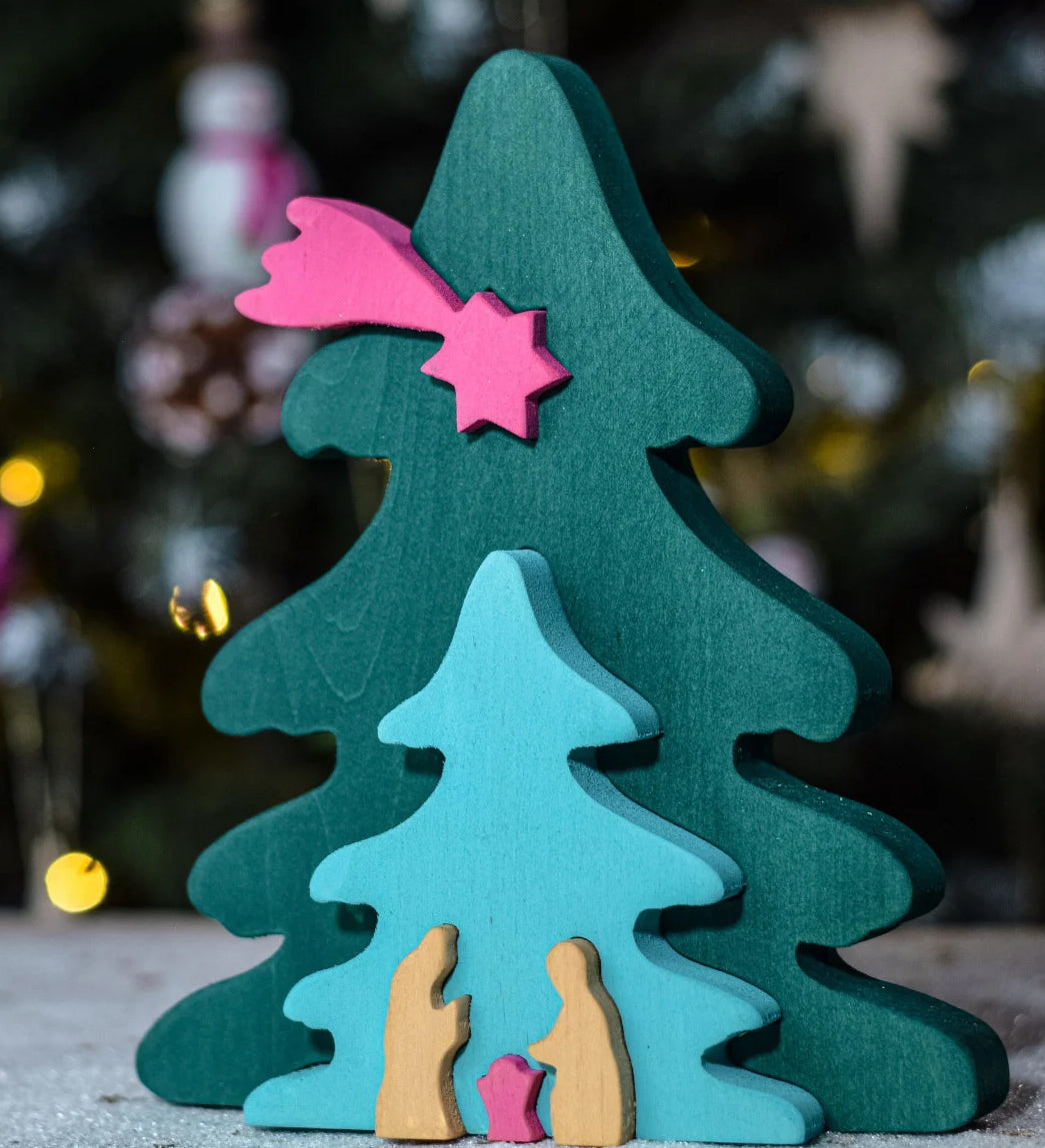 A Bumbu Christmas Tree Nativity Puzzle in a Fuchsia colour way in front of a Christmas tree. 