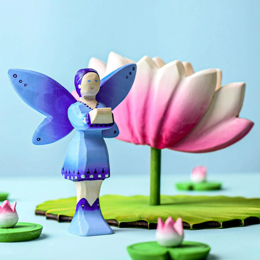 A Bumbu Water Fairy stood on top of a Bumbu Large Wooden Lotus Flower. A pink and white Lotus Flower with a green stalk and green base