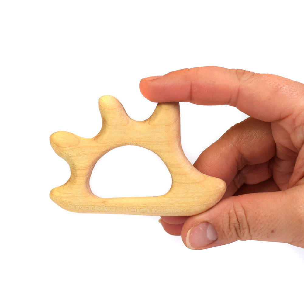 Close up of a childs hand holding the plastic-free Bumbu hedgehog baby teether on a white background