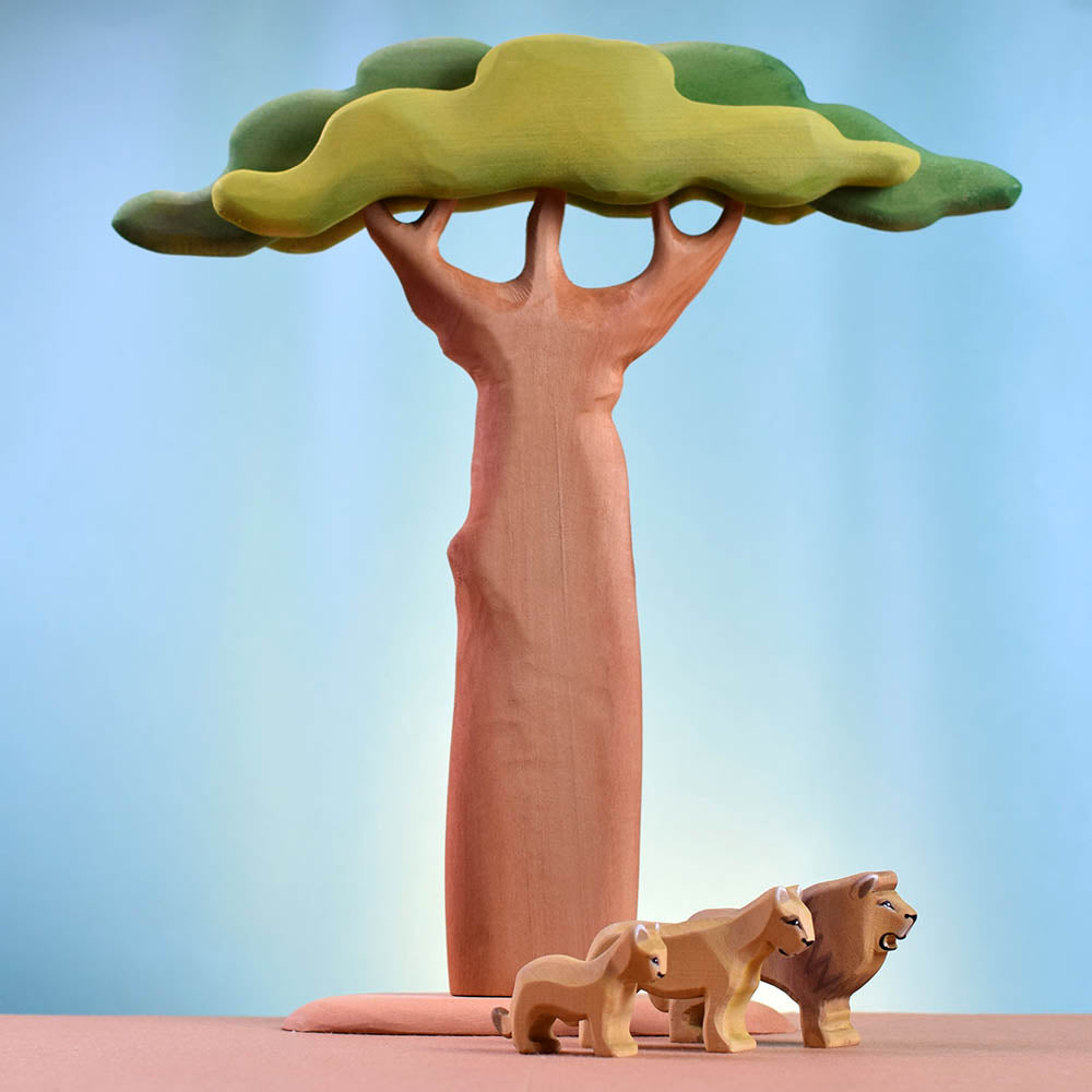 Bumbu plastic-free wooden lion toy figures stood in front of a Bumbu tall baobab tree