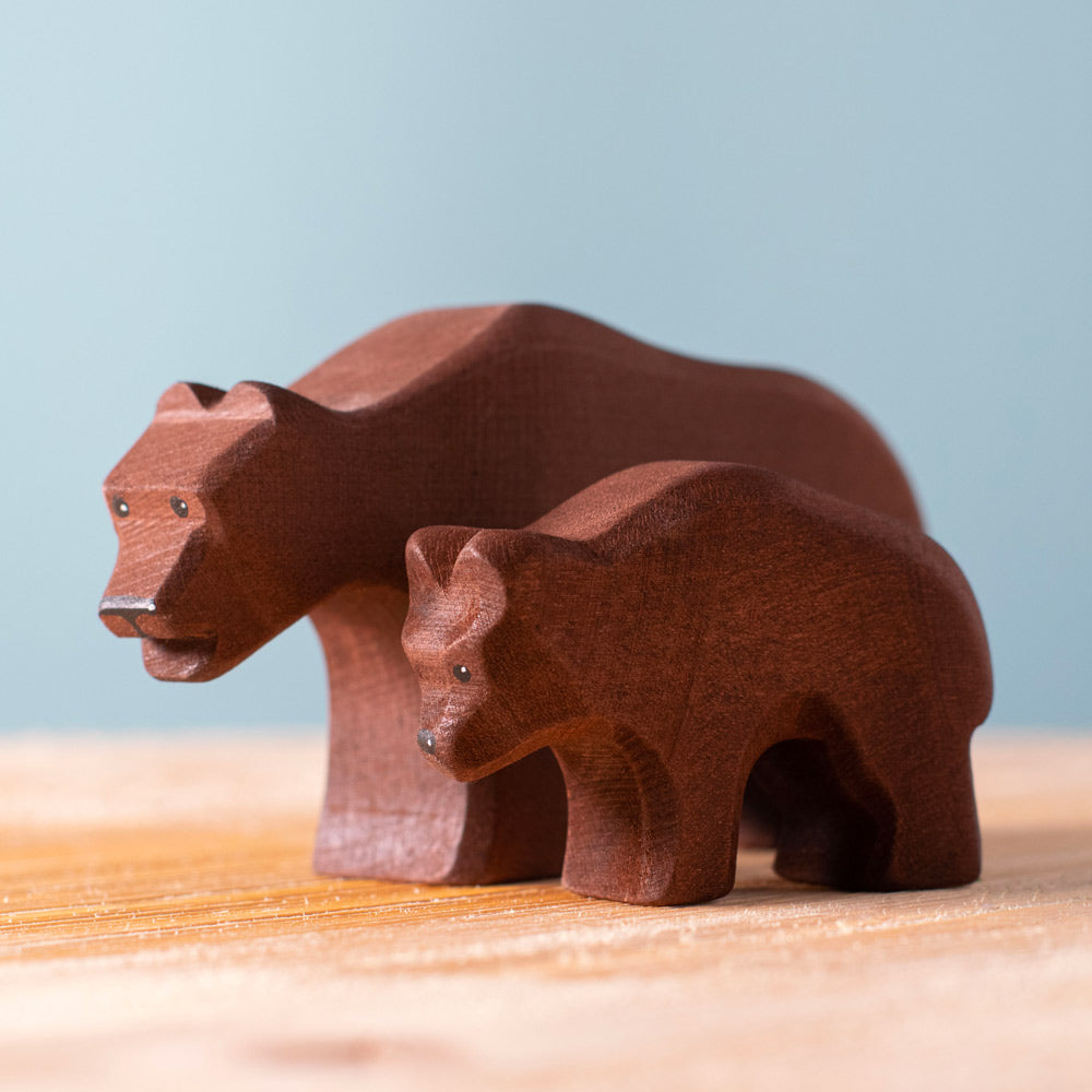 Close up of the Bumbu plastic-free bear cub toy next to the brown bear figure on a wooden worktop