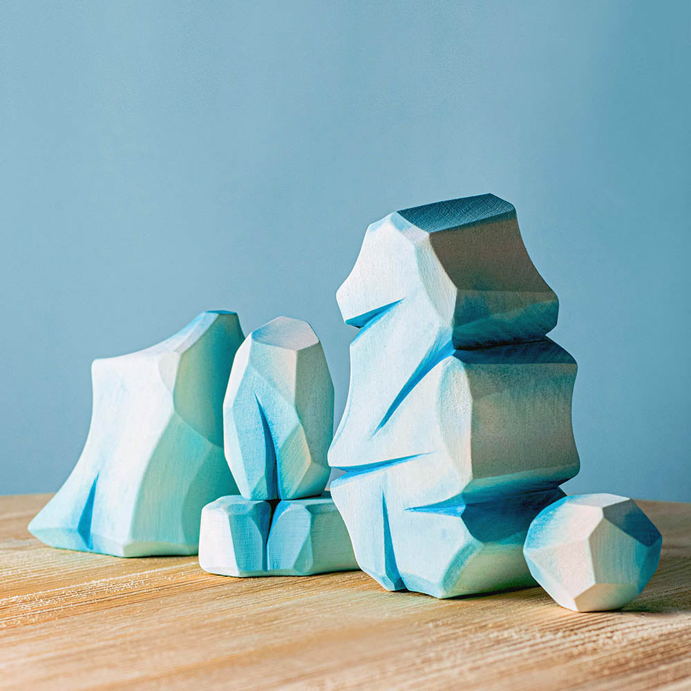 Bumbu hand carved wooden icy rocks on a wooden worktop in front of a blue background