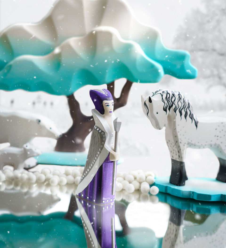 Bumbu wooden snow queen toy figure stood on a mirror next to a white horse figure and a Bumbu winter maple tree