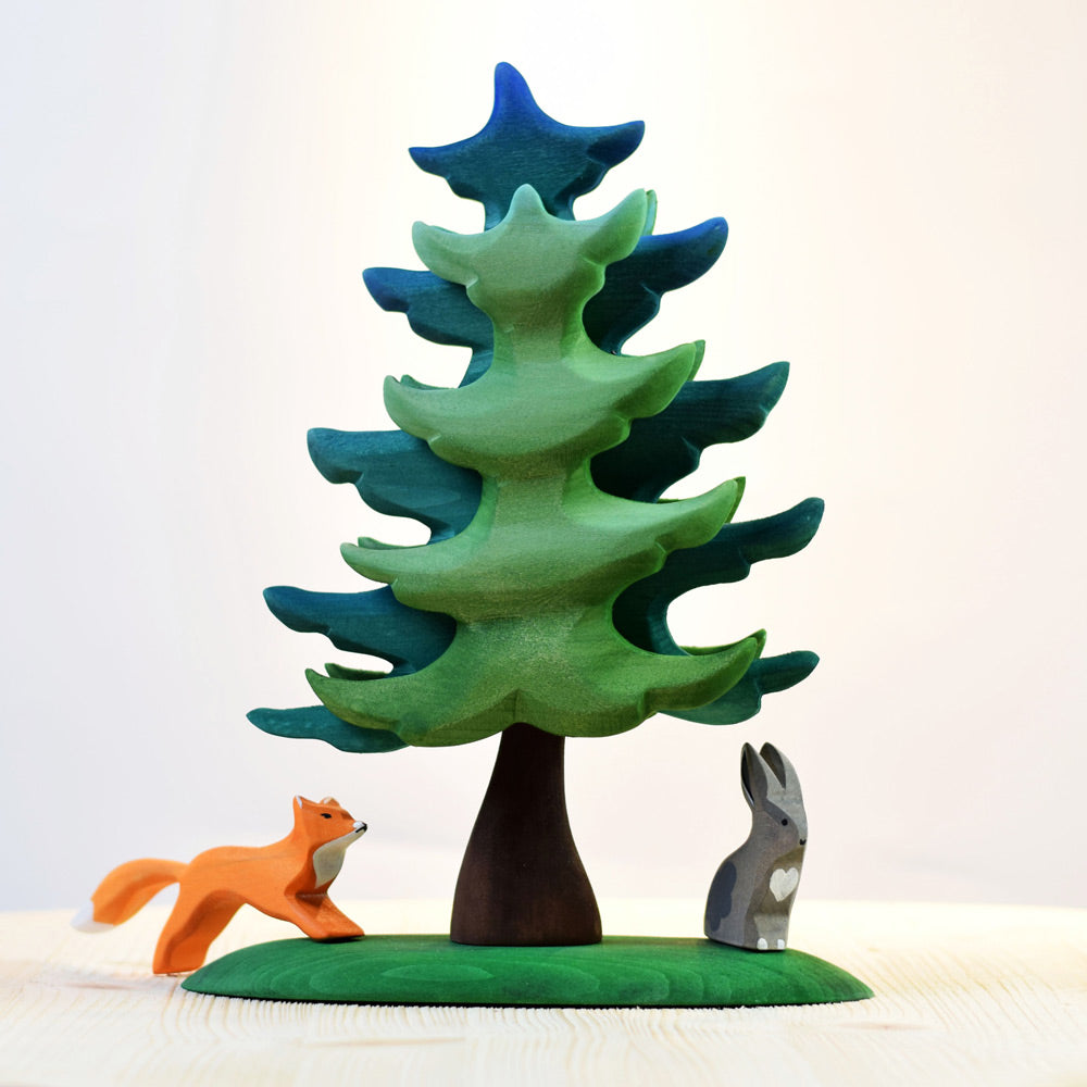 Bumbu eco-friendly wooden rabbit and fox toys stood next to the Bumbu handmade large spruce tree toy on a beige worktop