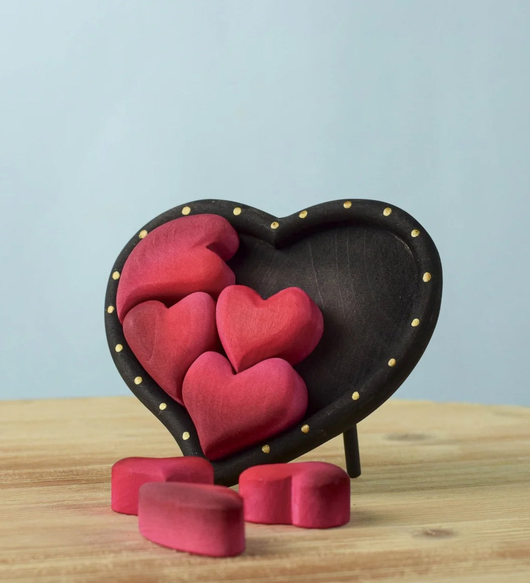 Bumbu wooden red hearts puzzle set in a wooden heart frame standing on a table with heart pieces on the table